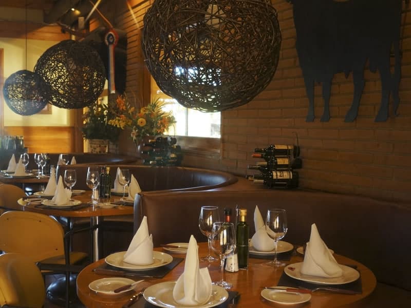 Comedor de Los Ganaderos, con muro de ladrillo y mesas preparadas